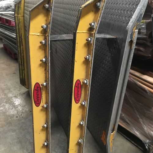 A group of branded dock plates standing on their end on a concrete warehouse floor.