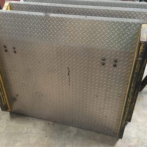 A series of dock plates standing on end in a warehouse with a concrete floor