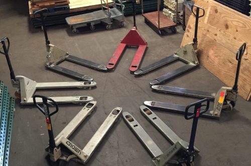 Various pallet jacks arranged in a circle in a warehouse with other material handling equipment.