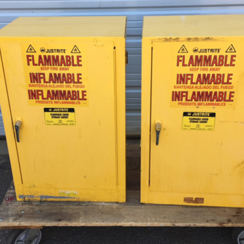 Two Flammable Item Cabinets sit on a wheeled cart outside a warehouse.