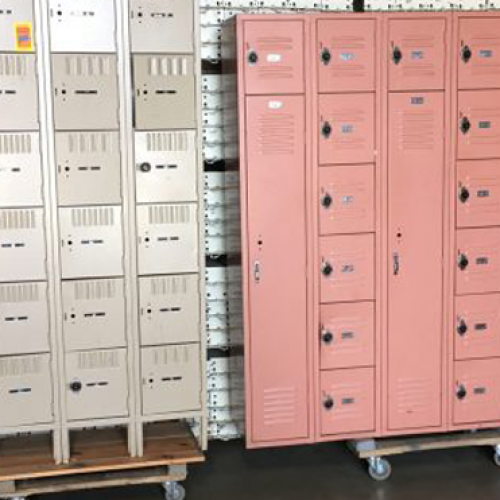 Used storage lockers in pink and cream colors sitting on wooden dollies in a warehouse environment.